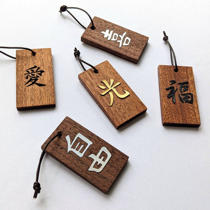 Kanji Mini Talisman – handgefertigter Holz Anhänger-Glücksbringer mit vergoldeter Lederprägung